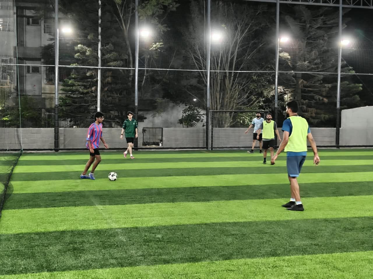 Players in a night football match under floodlights